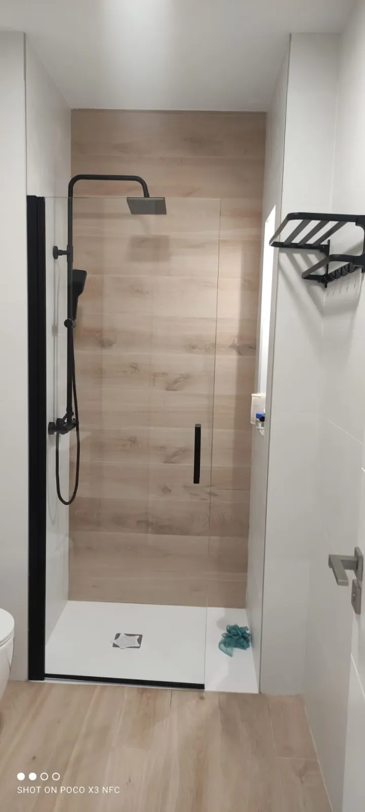 Reforma de baño con plato de ducha, mampara negra y grifería negra en Valladolid